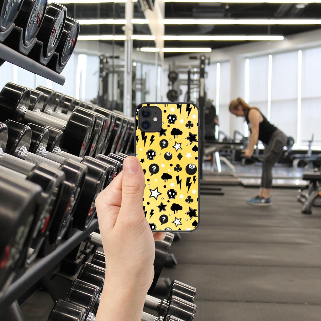 Telefoonhoesje iPhone 11 Punk Geel in gebruik in sportschool, met skulls en sterren design op een gele achtergrond.