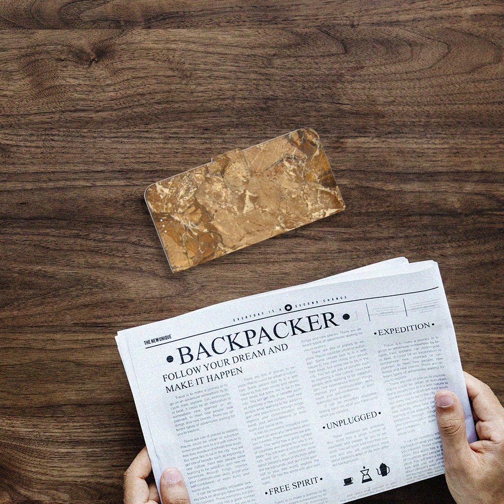 OnePlus 9 Bookcase Marmer Creme op een houten tafel met een krant ernaast.