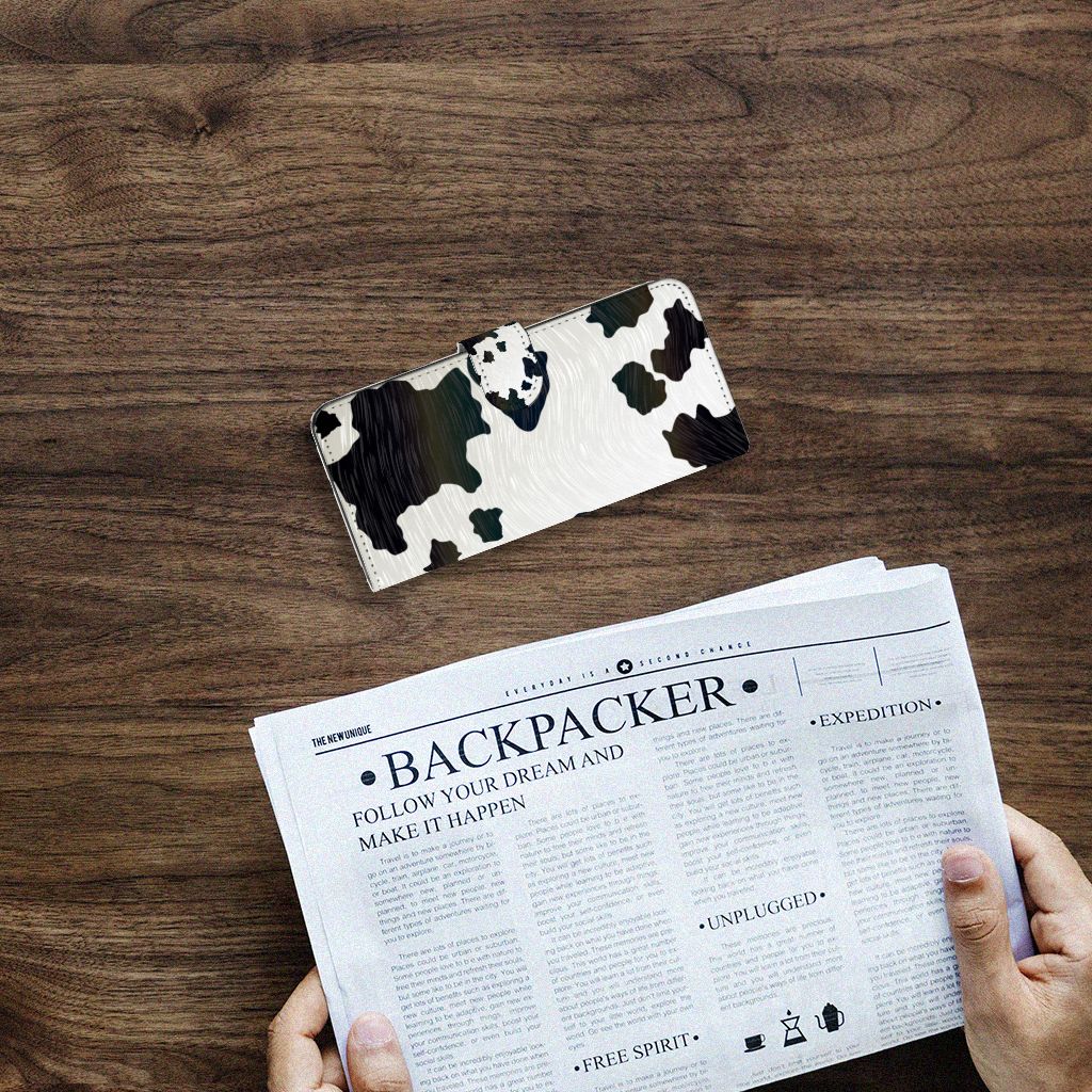 Samsung Galaxy A14 4G Telefoonhoesje met Pasjes Koeienvlekken op een houten tafel met krant.