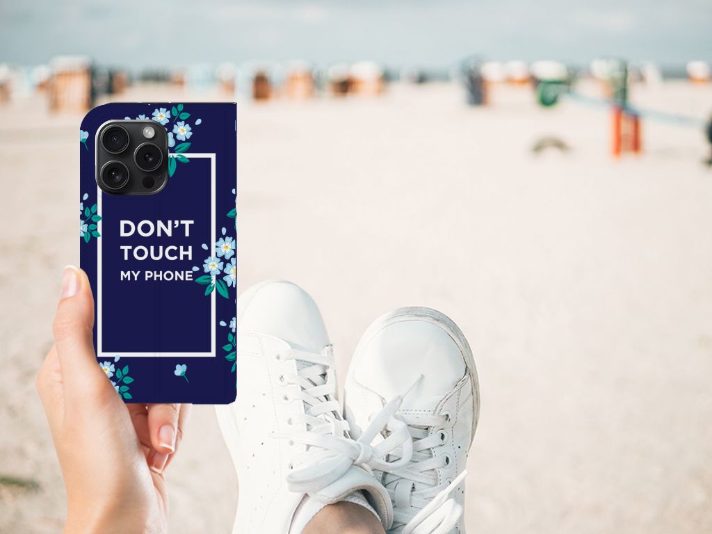 iPhone 15 Pro Design Case Flowers Blue DTMP met bloemen en tekst 'DON'T TOUCH MY PHONE' op het strand.