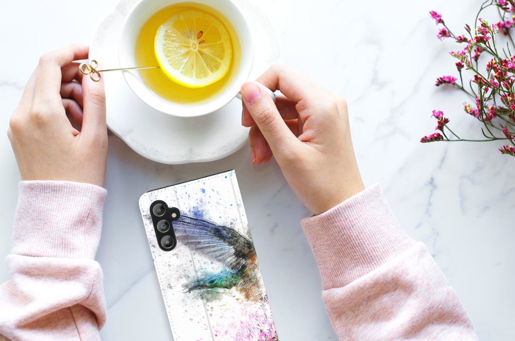 Bookcase Samsung Galaxy A14 5G Vogel naast een kopje thee met citroen op een marmeren tafel.