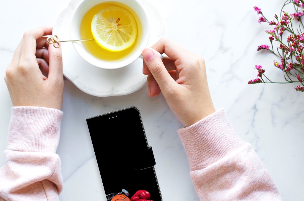 Xiaomi 12 | 12X Wallet Case met Pasjes Sports liggend op een tafel naast een hand met een kopje thee.