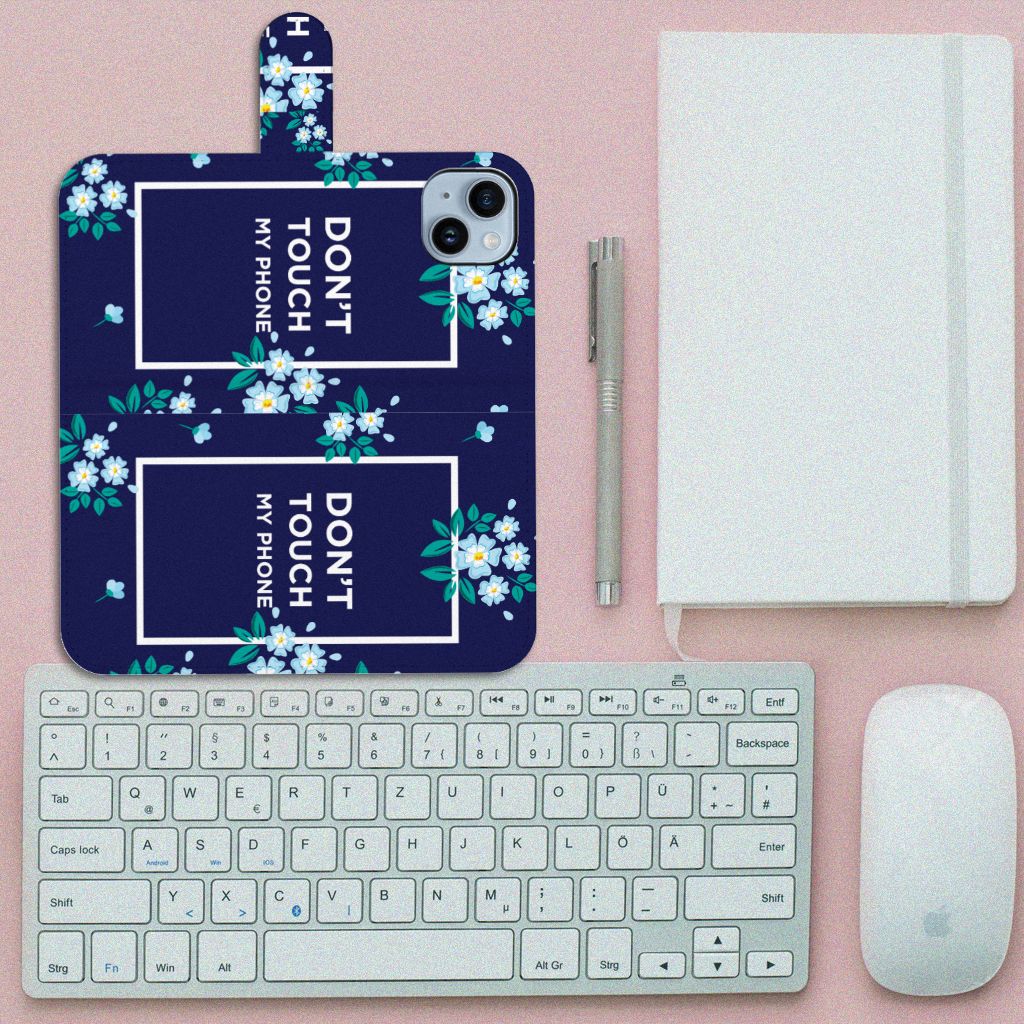 iPhone 15 Plus Portemonnee Hoesje Flowers Blue DTMP met bloemenprint en tekst 'DON'T TOUCH MY PHONE' op een bureau.