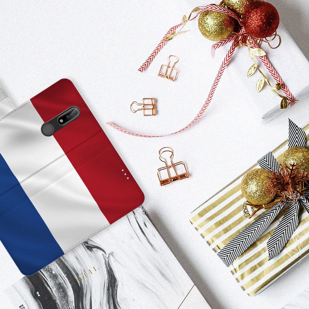 Nokia 2.4 Bookstyle Case Nederlandse Vlag met Franse vlagdesign en kerstdecoraties op tafel.
