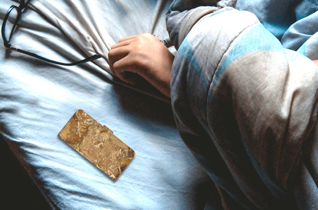 Motorola Moto E7i Power | E7 Power Bookcase Marmer Creme en hand op bed met dekens.