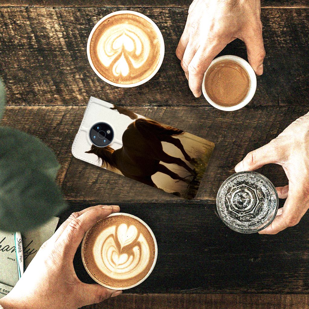 Nokia G50 Hoesje maken Design Cowboy met paardenprint op een houten tafel met koffie.