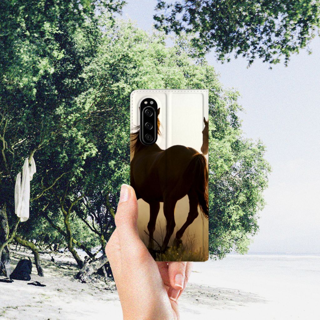 Sony Xperia 5 Hoesje maken Design Cowboy met paardenprint in hand bij een strandomgeving.