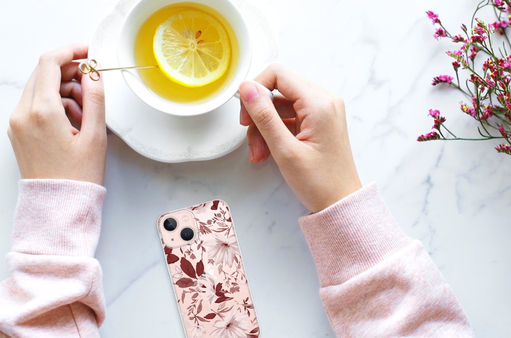 Hoesje maken iPhone 13 mini Watercolor Flowers met bloemenprint, naast een kopje kruidenthee đĩ op een marmeren tafel.