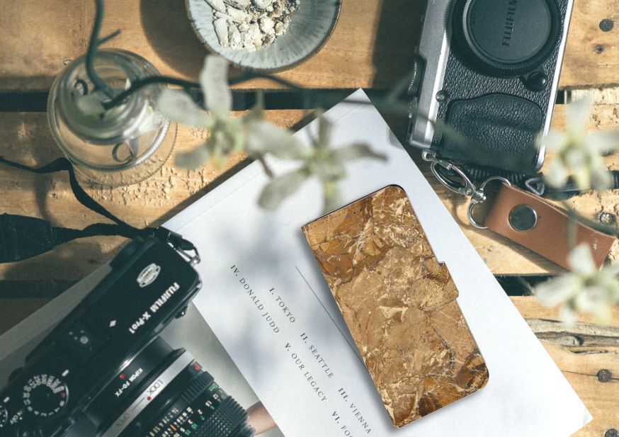 Samsung Galaxy A20s Bookcase Marmer Creme op een houten tafel met vintage camera's en planten.