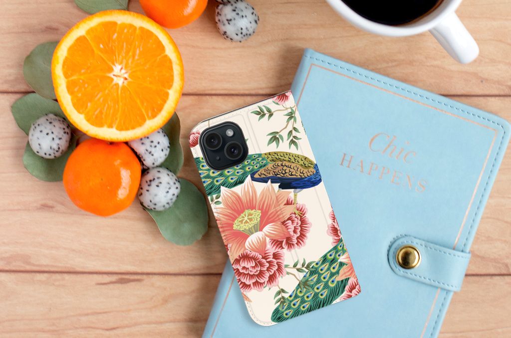 Hoesje maken voor iPhone 15 Pink Peacock met kleurrijke bloemen en pauwen op een houten tafel.