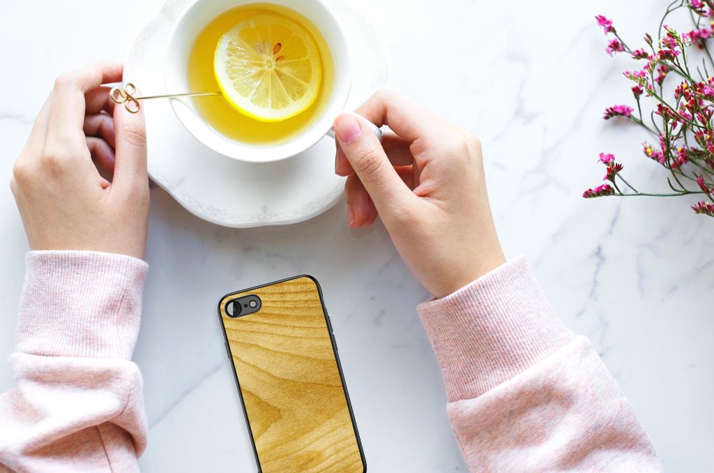 Handen met een telefoonhoesje in houten print naast een kopje thee met citroen, passend voor iPhone SE 2022 | SE 2020 | 7/8 Houten Print Telefoonhoesje Licht Hout.