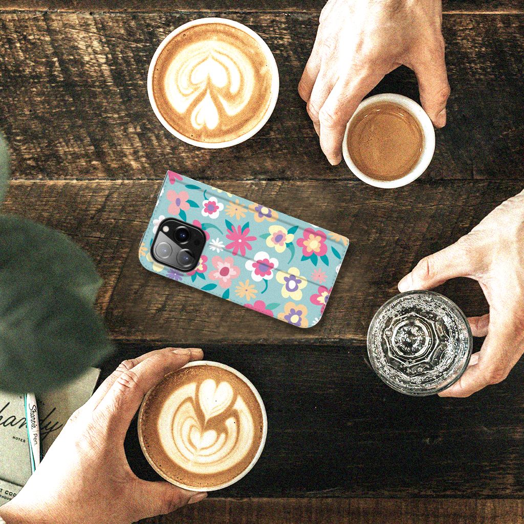 iPhone 14 Pro Smart Cover Flower Power met kleurrijk bloemenontwerp, geplaats naast koffie in een gezellige setting.