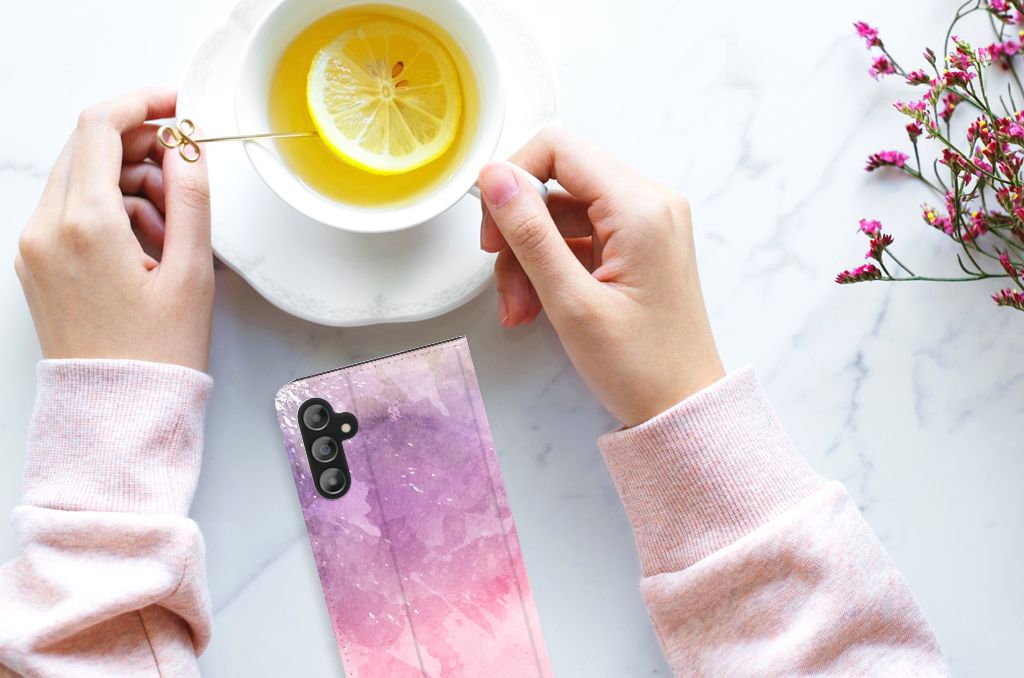 Bookcase Samsung Galaxy A14 5G Pink Purple Paint resting on a marble surface next to a cup of tea.