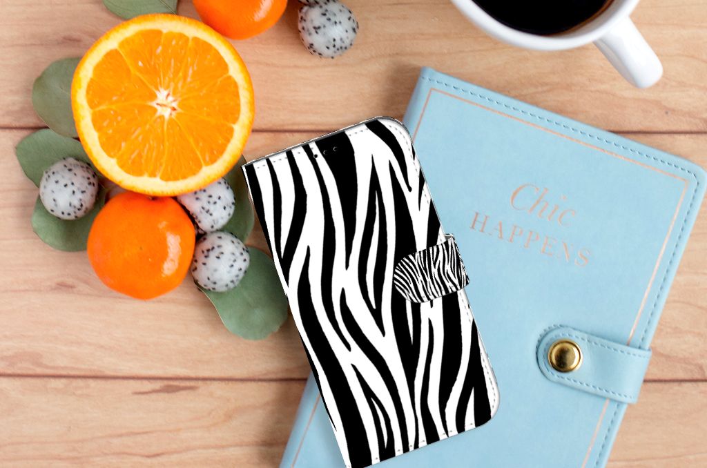 iPhone 14 Plus Telefoonhoesje met Pasjes Zebra op een houten tafel met fruit en een notitieboekje.