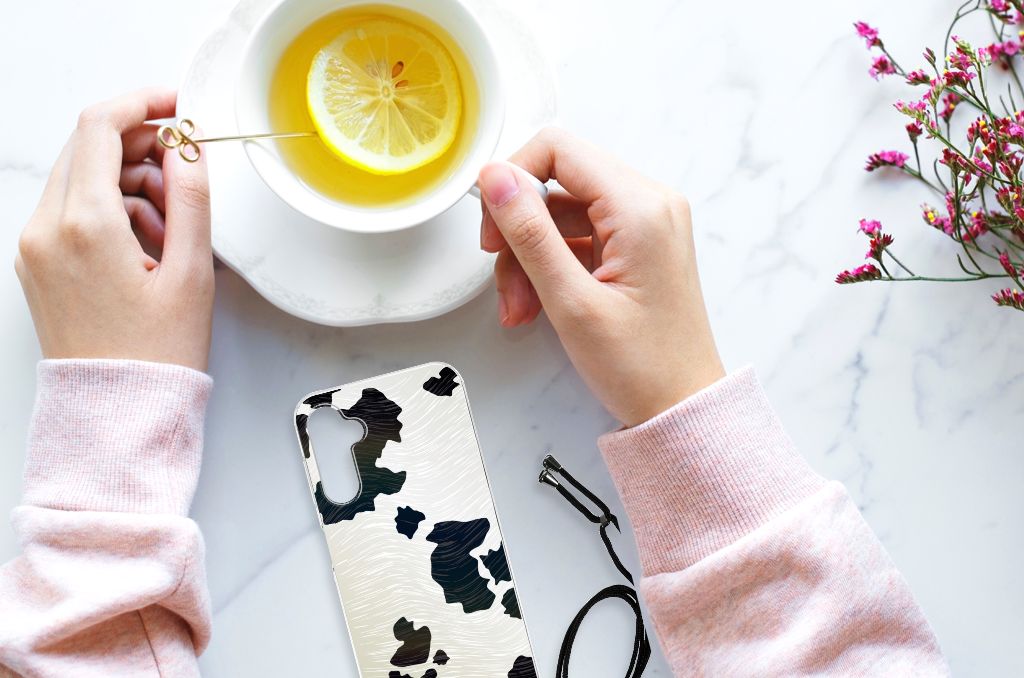 Samsung Galaxy A14 5G Case Anti-shock Koeienvlekken naast een kopje met citroen op een elegante tafel.