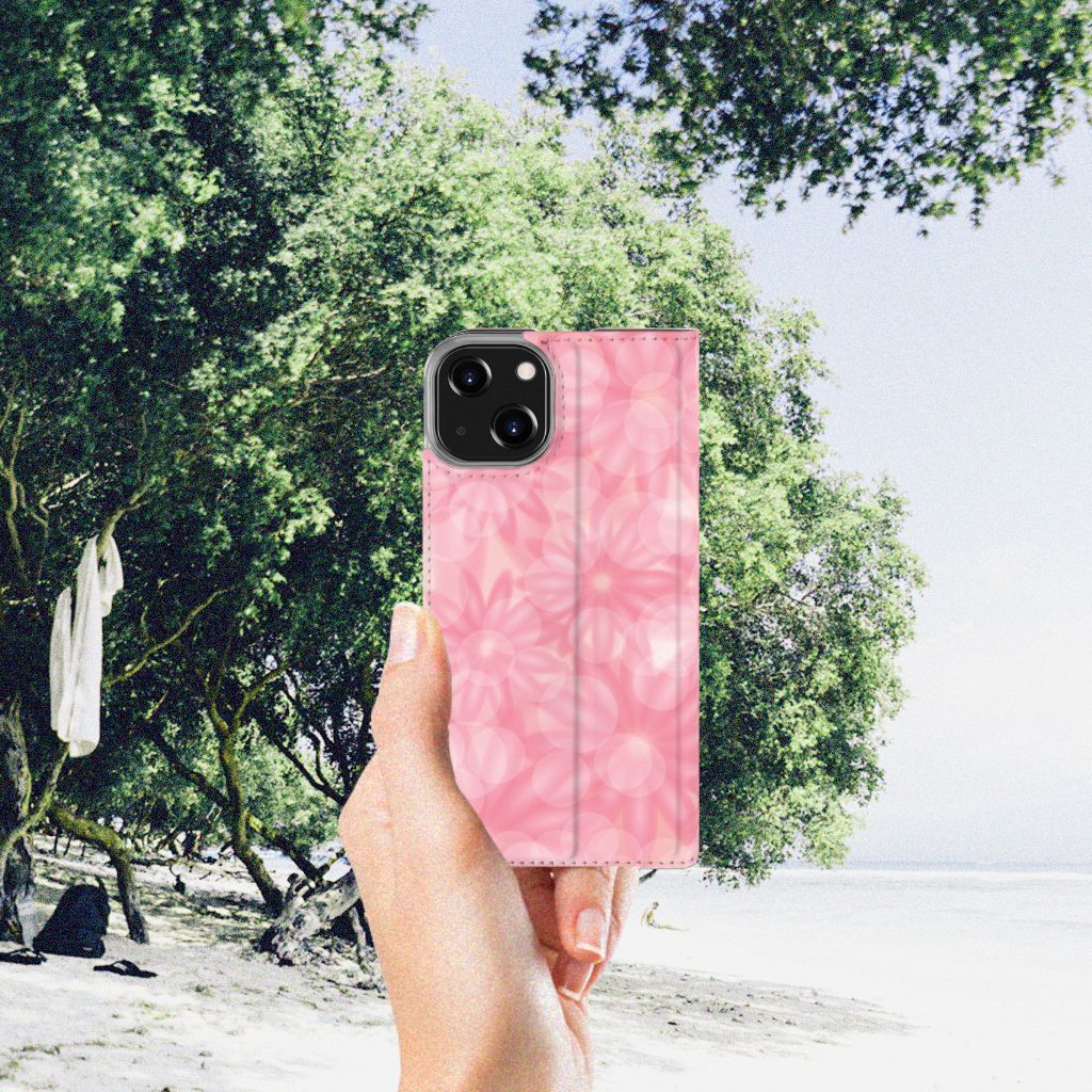 iPhone 14 Smart Cover Spring Flowers in hand on a beach with green trees in background.