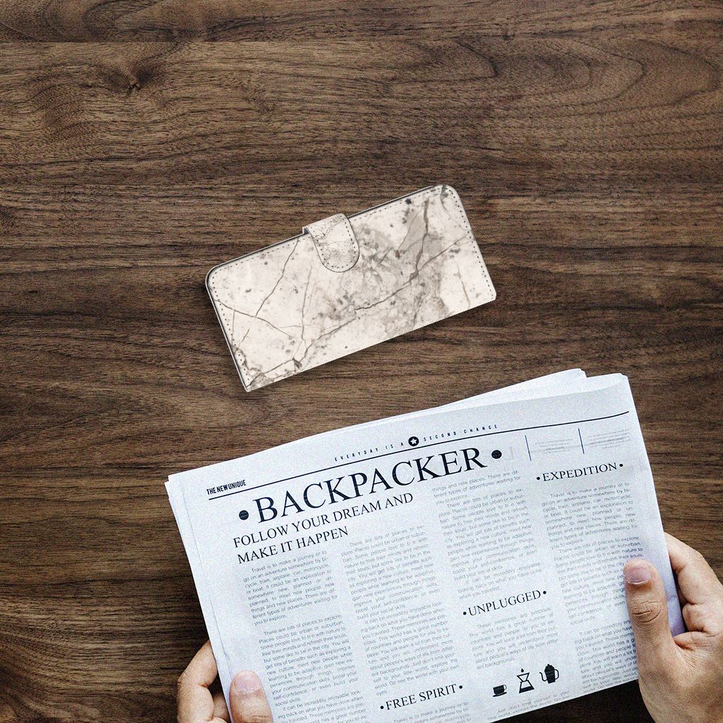 Samsung Galaxy A14 4G Bookcase Marmer Beige op een houten tafel met een krant ernaast.