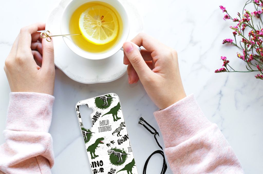 Hand holding a Case Anti-shock voor Samsung Galaxy A14 5G Dinosaurus next to tea with lemon.