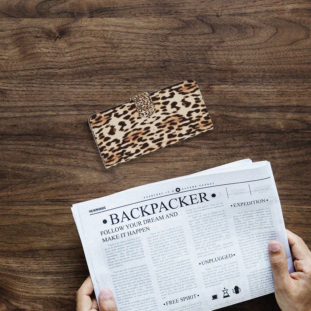 Samsung Galaxy A14 4G Telefoonhoesje met Pasjes Leopard op een houten tafel met een krant.
