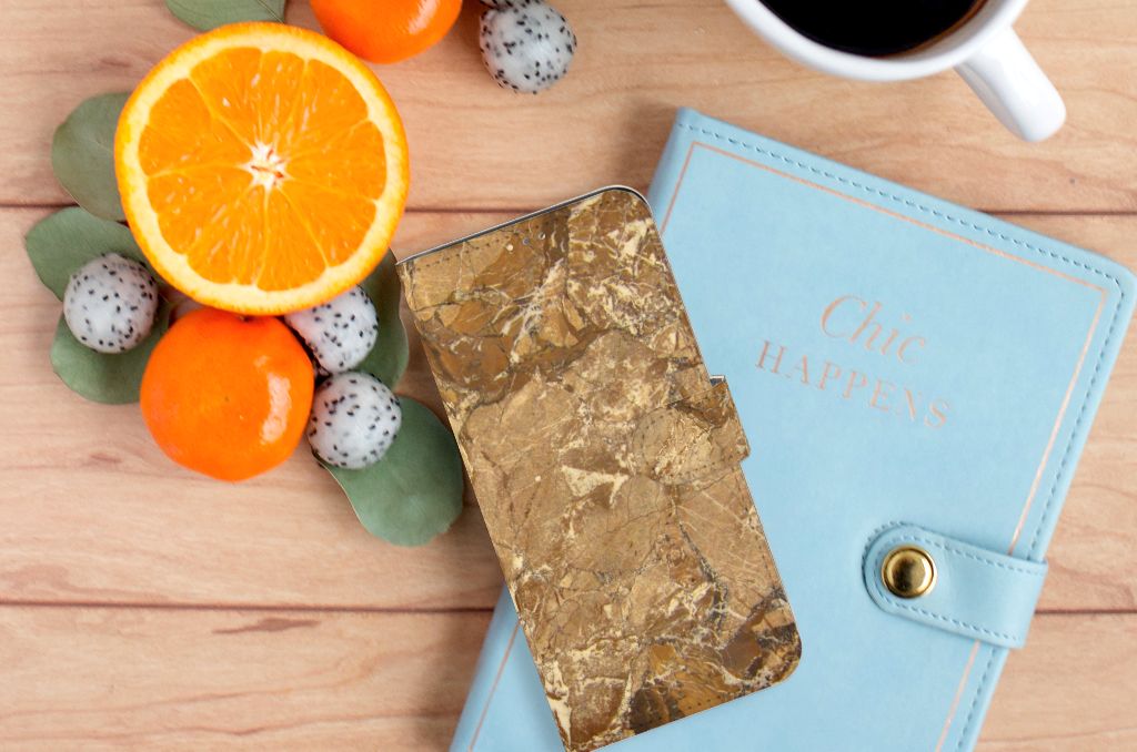 OPPO A15 Bookcase Marmer Creme naast een blauw notitieboekje en fruit op houten tafel.