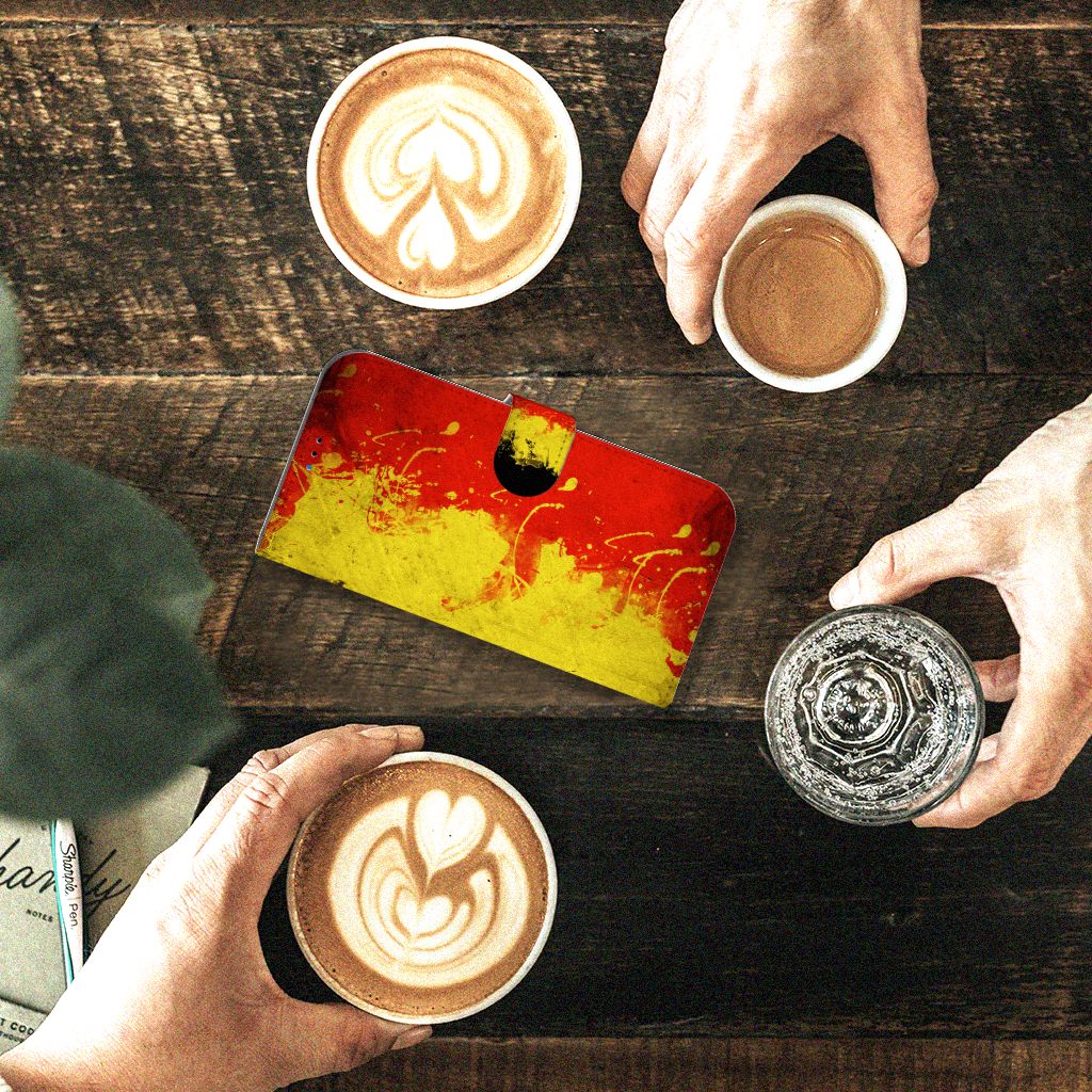 iPhone 14 Pro Max Bookstyle Case België met Belgische kleuren, naast kopjes koffie en water op een houten tafel.