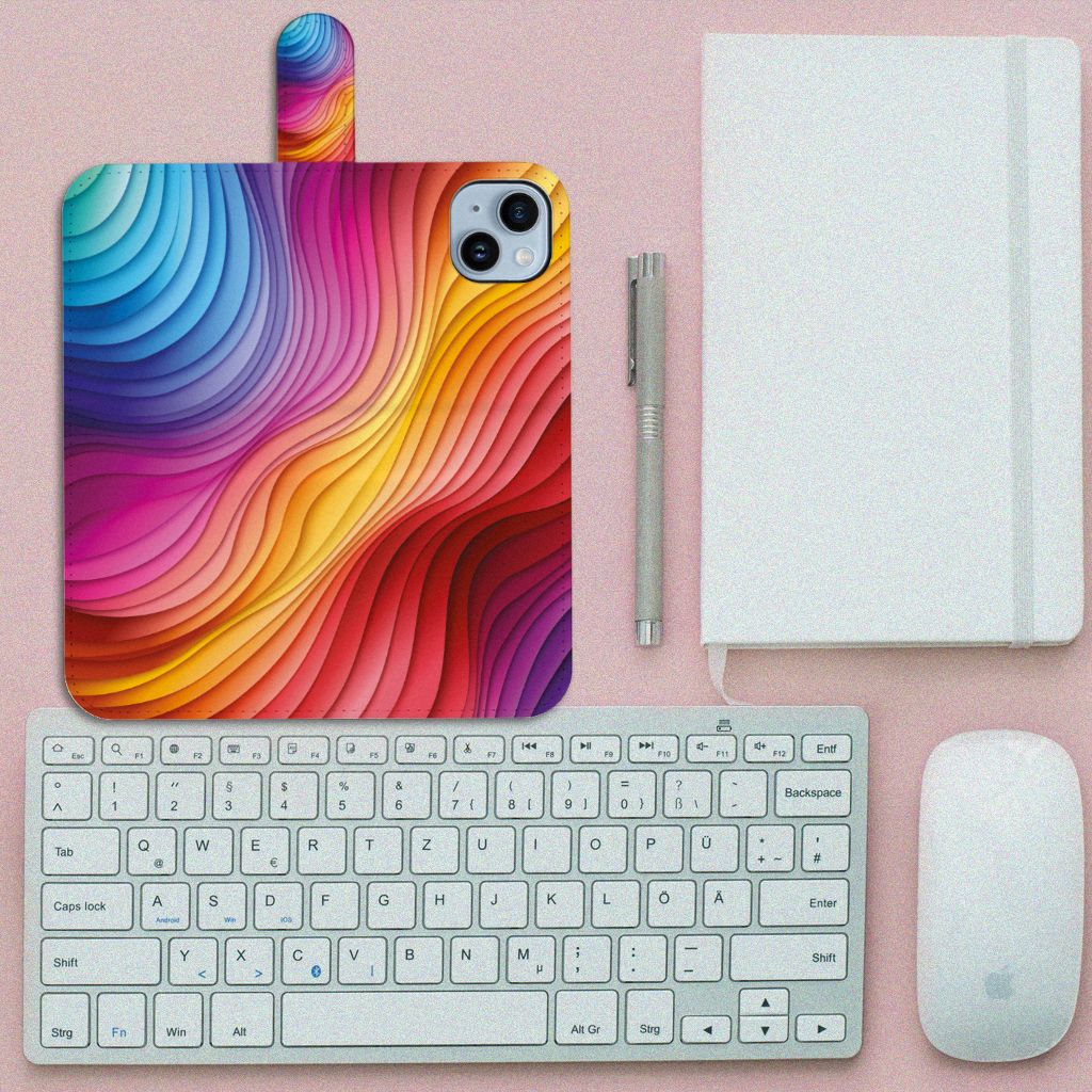 Book Case voor iPhone 15 Plus Regenboog met kleurrijk ontwerp en golfpatronen đ op bureau met toetsenbord.