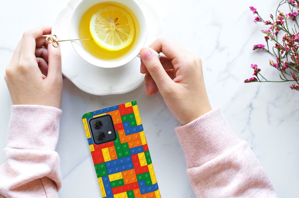 Motorola Moto G84 Hoesje met Magneet Blokken smartphone handen thee tafel