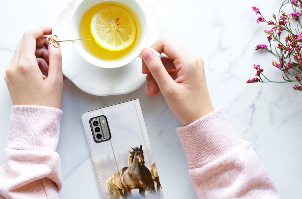 Nokia G22 Hoesje maken Paarden met een paardendetail, wordt vastgehouden met een kopje thee.