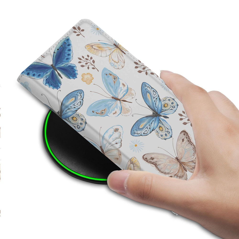 Samsung Galaxy S26 Telefoonhoesje Vlinder detail met vlinderdessin op PU-leer terwijl het telefoonhoesje op een draadloze oplader ligt.