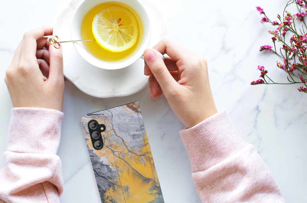 Samsung Galaxy A14 4G Standcase Marble Blue Gold met een kopje thee en citroen op een marmeren tafel.