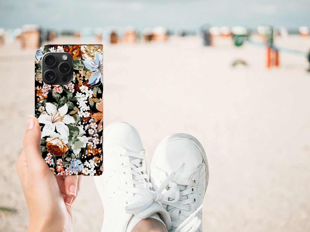 Smart Cover voor iPhone 15 Pro Dark Flowers met bloemenprint in hand op het strand.