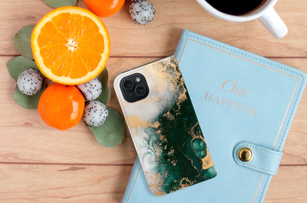 Standcase voor iPhone 15 Marmer Groen met marmerdesign, citrusvruchten en notitieboekje op houten tafel.