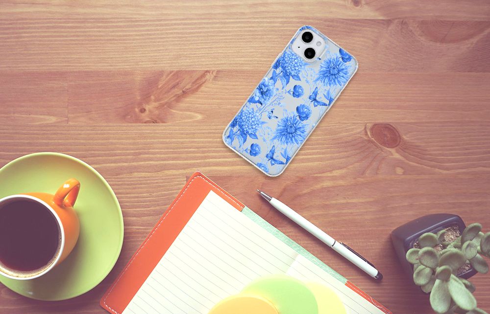 TPU Case voor iPhone 15 Plus Flowers Blue op een houten tafel met koffie en notities.