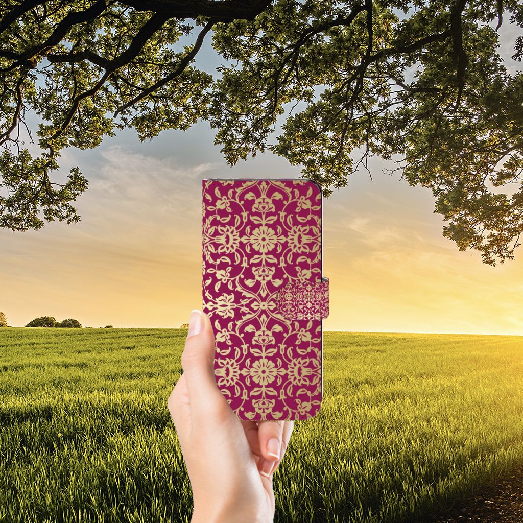 Hand holding a Wallet Case OPPO Reno8 T 5G Barok Pink against a picturesque sunset field, showcasing style and protection.