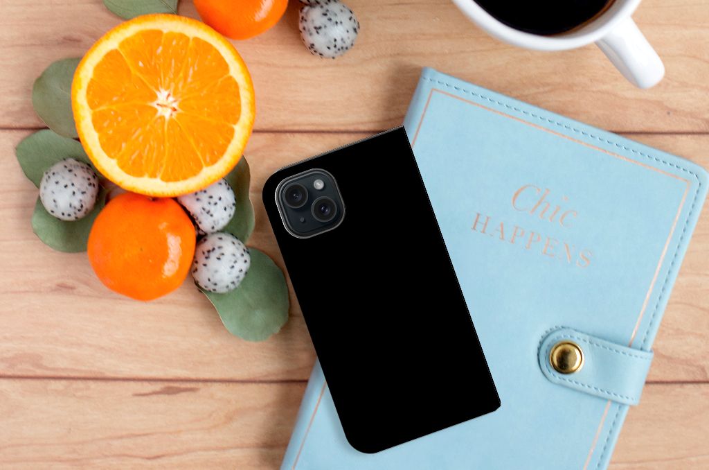 iPhone 15 Magnet Case Cow op een tafel met fruit en een notitieboekje, ideaal voor stijl en functionaliteit.