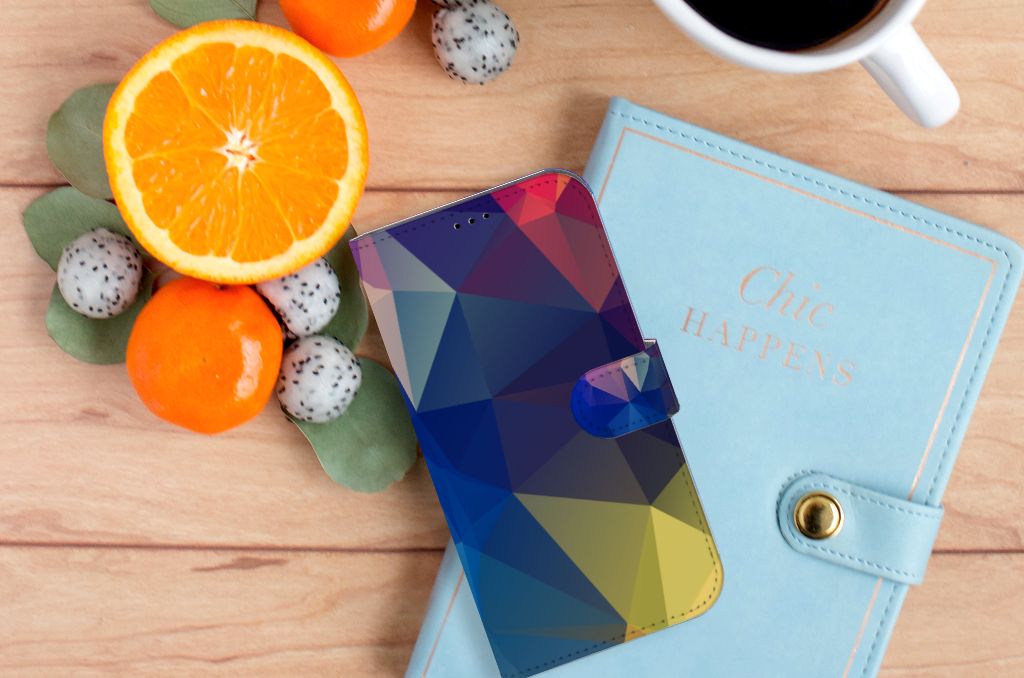 iPhone 14 Plus Book Case Polygon Dark met kleurrijk abstract design, naast een notitieboek en fruit đ.