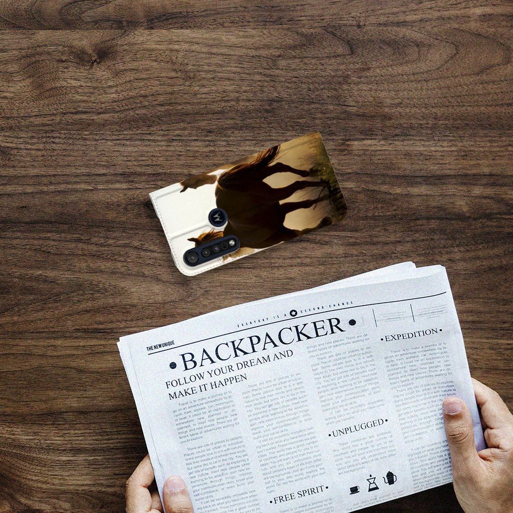 Motorola G8 Plus Hoesje maken Design Cowboy met paardenprint op een houten tafel met een krant ernaast.