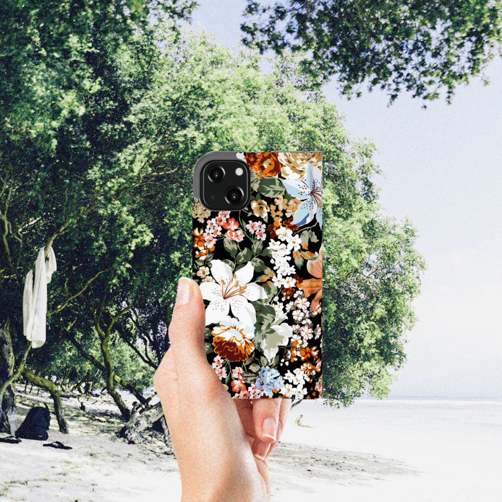 Smart Cover voor iPhone 13 Dark Flowers met bloemenprint in hand voor een strandachtige achtergrond.