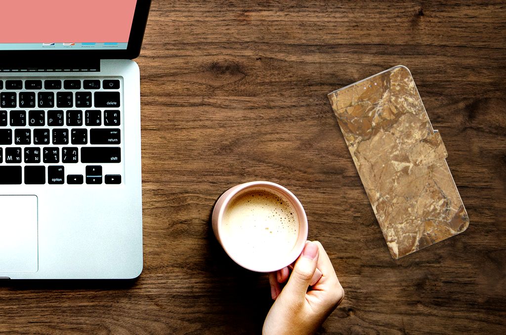 Samsung Note 10 Lite Bookcase Marmer Creme naast een laptop en een kop koffie op een houten tafel.