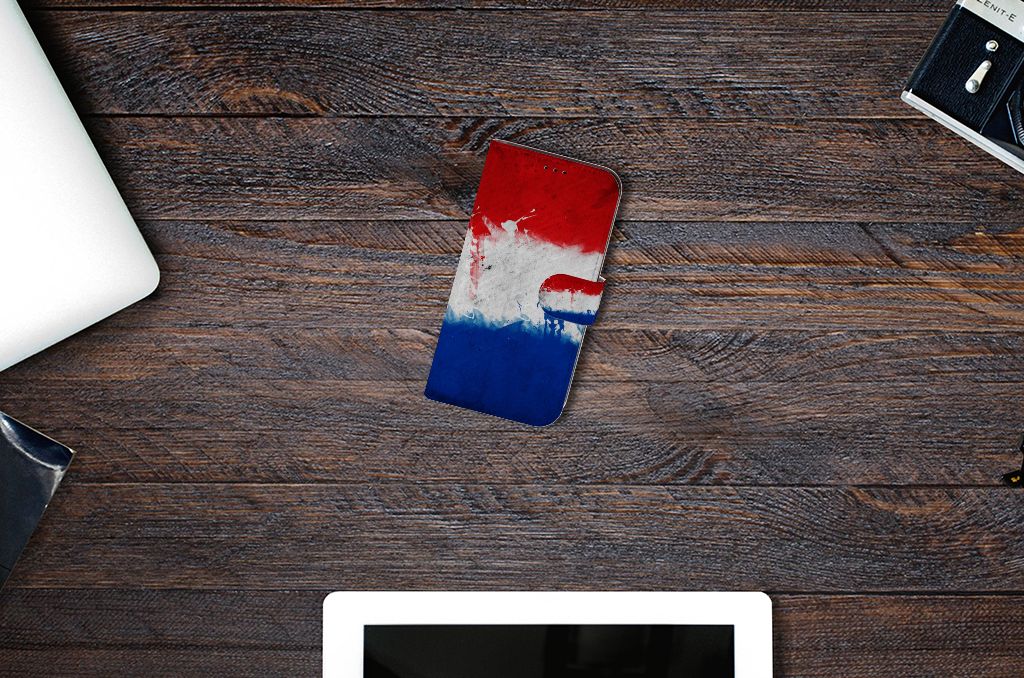 Apple iPhone 13 Bookstyle Case Nederland op een houten tafel met een laptop en tablet ernaast.