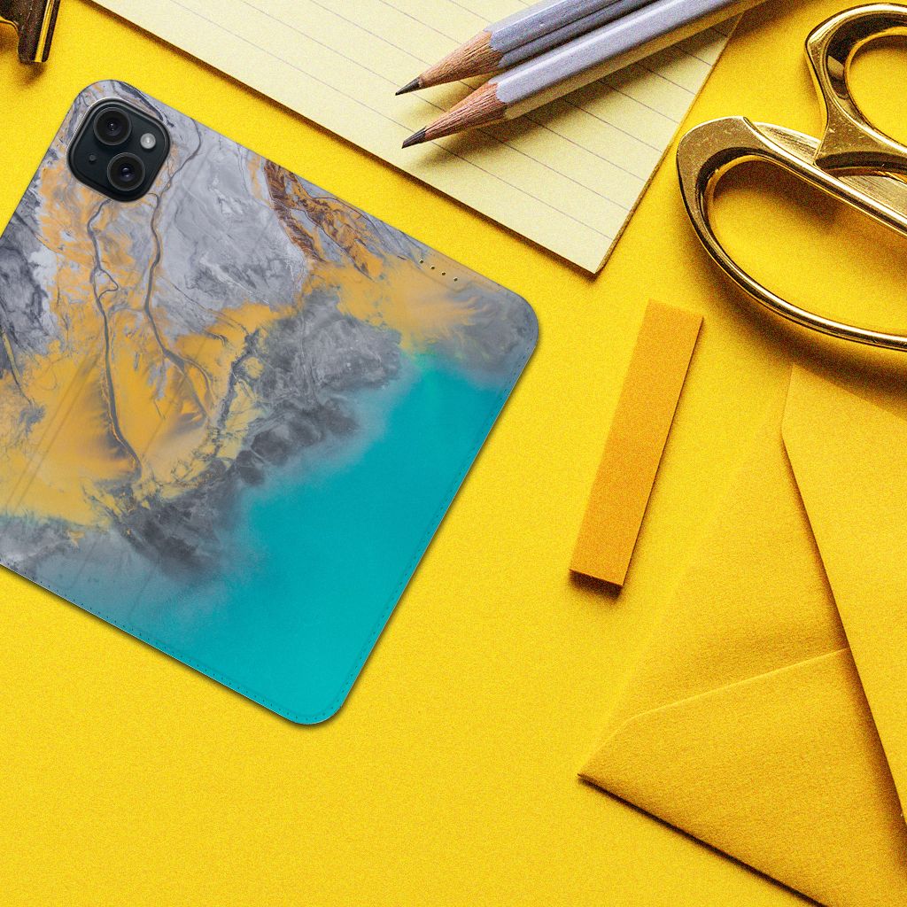 iPhone 15 Plus Standcase Marble Blue Gold met marmerdesign in blauw en goud op een bureau met kantoorbenodigdheden