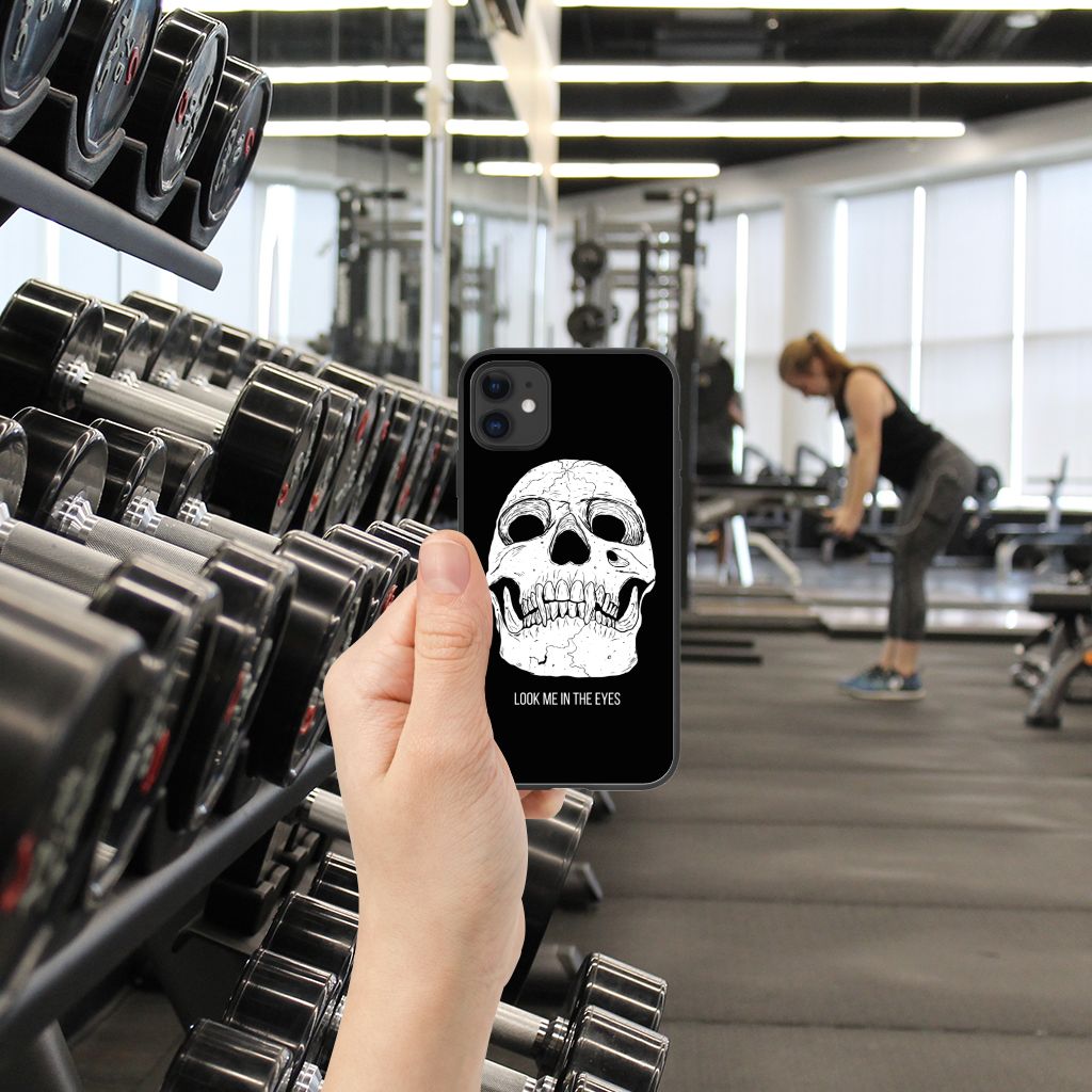 Telefoonhoesje iPhone 11 Skull Eyes met skull design in de sportschool, hand houdt het vast.