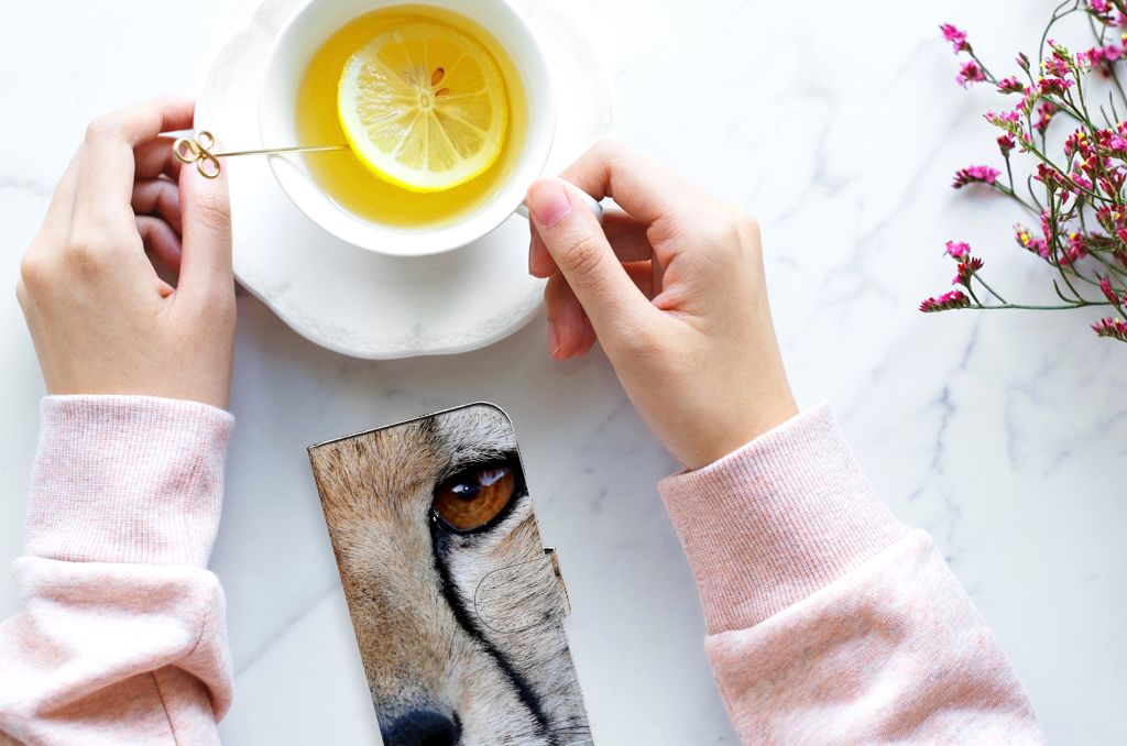 iPhone 15 Telefoonhoesje met Pasjes Cheetah naast een kopje met citroen en bloemen