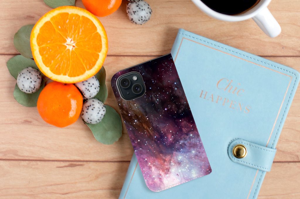 Stand Case voor iPhone 15 Galaxy met een prachtig sterrenhemel ontwerp en een notitieboekje op een houten tafel.