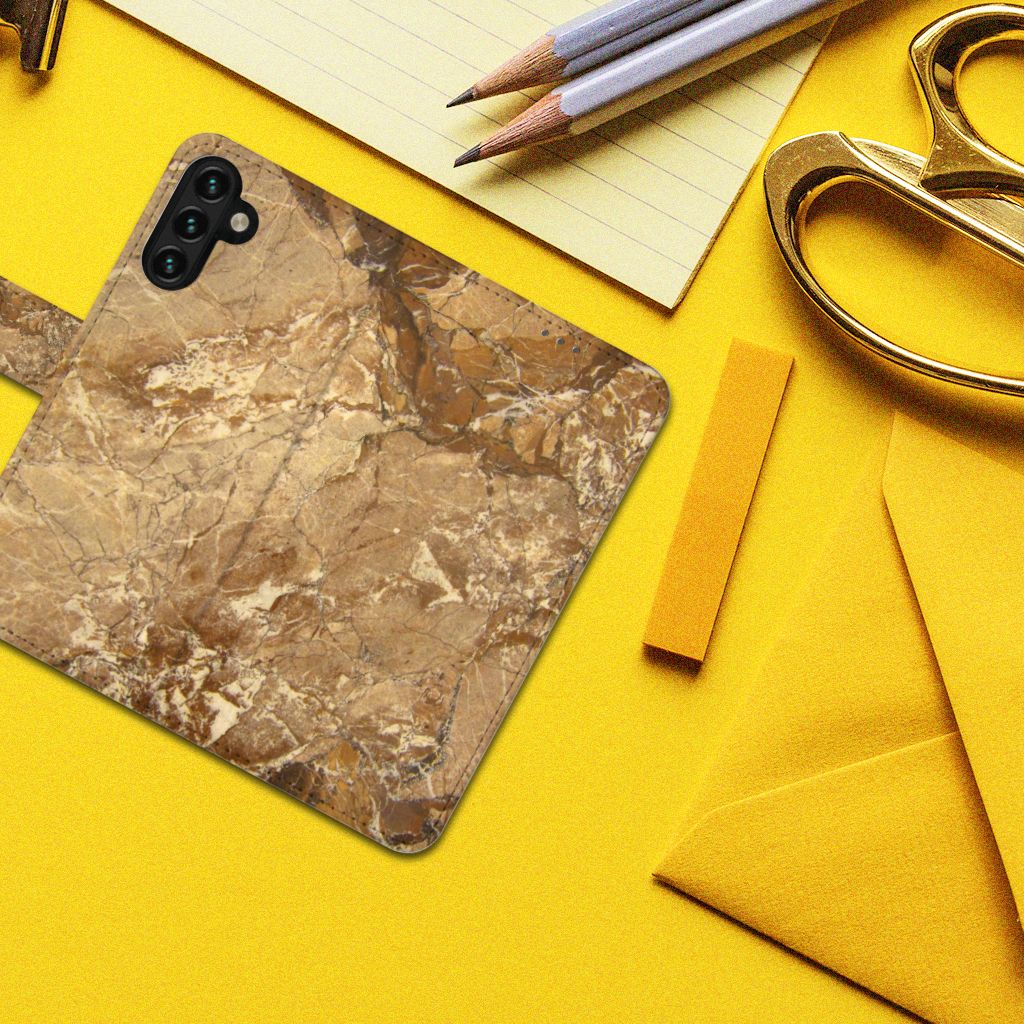 Samsung Galaxy A04s | Samsung Galaxy A13 5G Bookcase Marmer Creme op een gele achtergrond met kantoorbenodigdheden.
