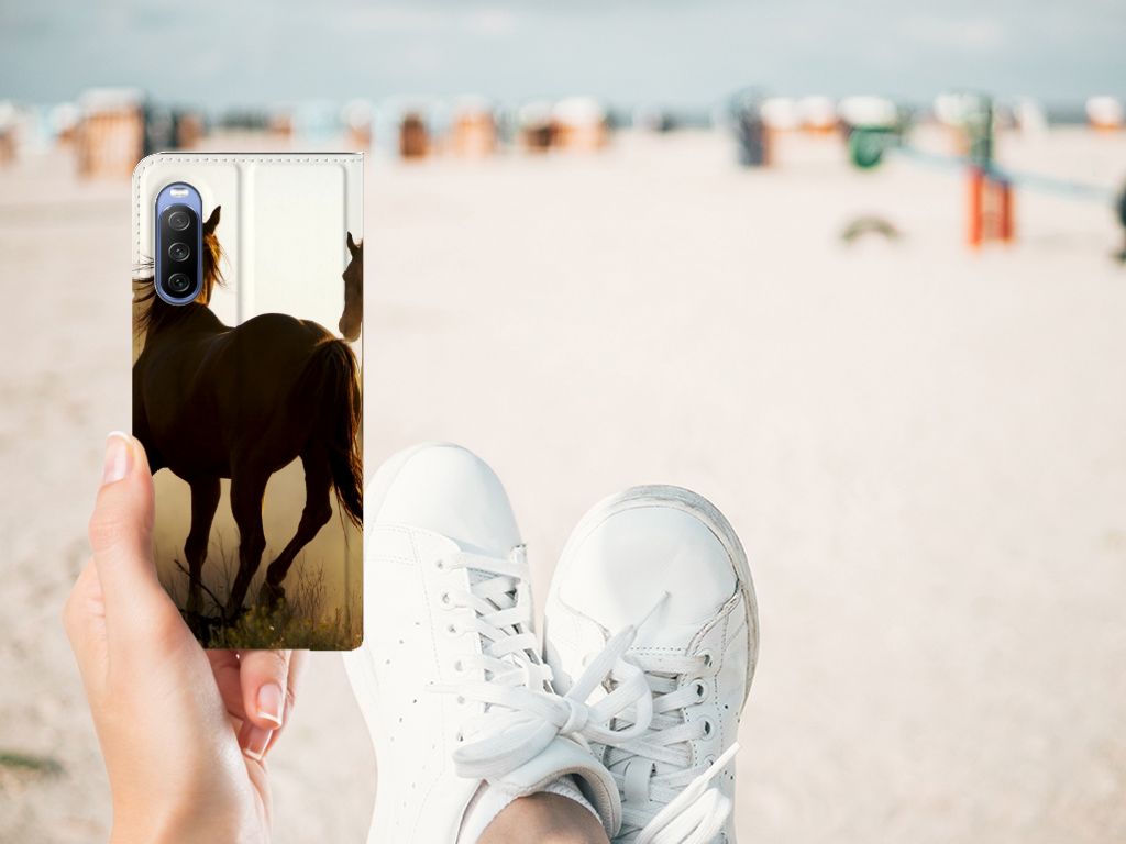 Sony Xperia 10 III Hoesje maken Design Cowboy met paardenprint op een smartphone in hand op het strand.