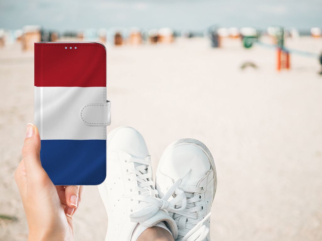 Huawei P40 Lite Bookstyle Case Nederlandse Vlag in hand, witte sneakers, strand op achtergrond.