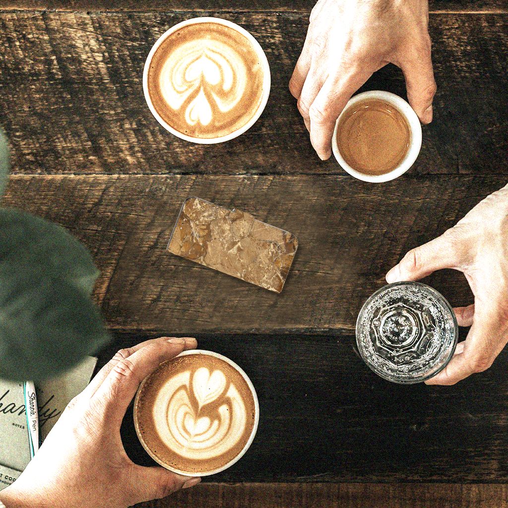 Mensen genieten van cappuccino's en espresso's op een houten tafel met een stuk marmer.