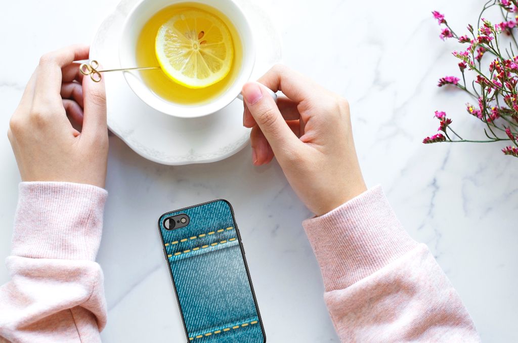 Hand holding a cup of lemon tea next to an iPhone SE 2022 | SE 2020 | 7/8 GSM Cover Jeans on a marble table.