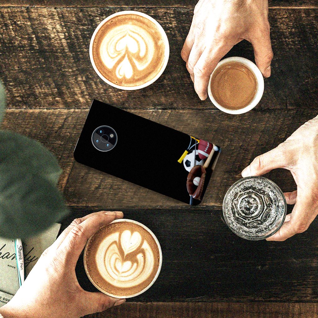 Nokia G50 Hippe Standcase Sports placed on a wooden table with coffee cups and a water glass.